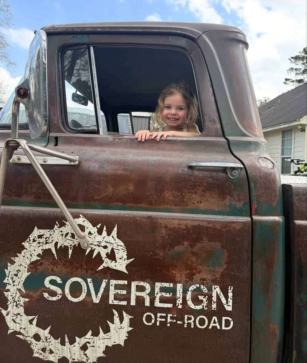 A smiling child in the window of the Sovereign Off-Road vintage truck